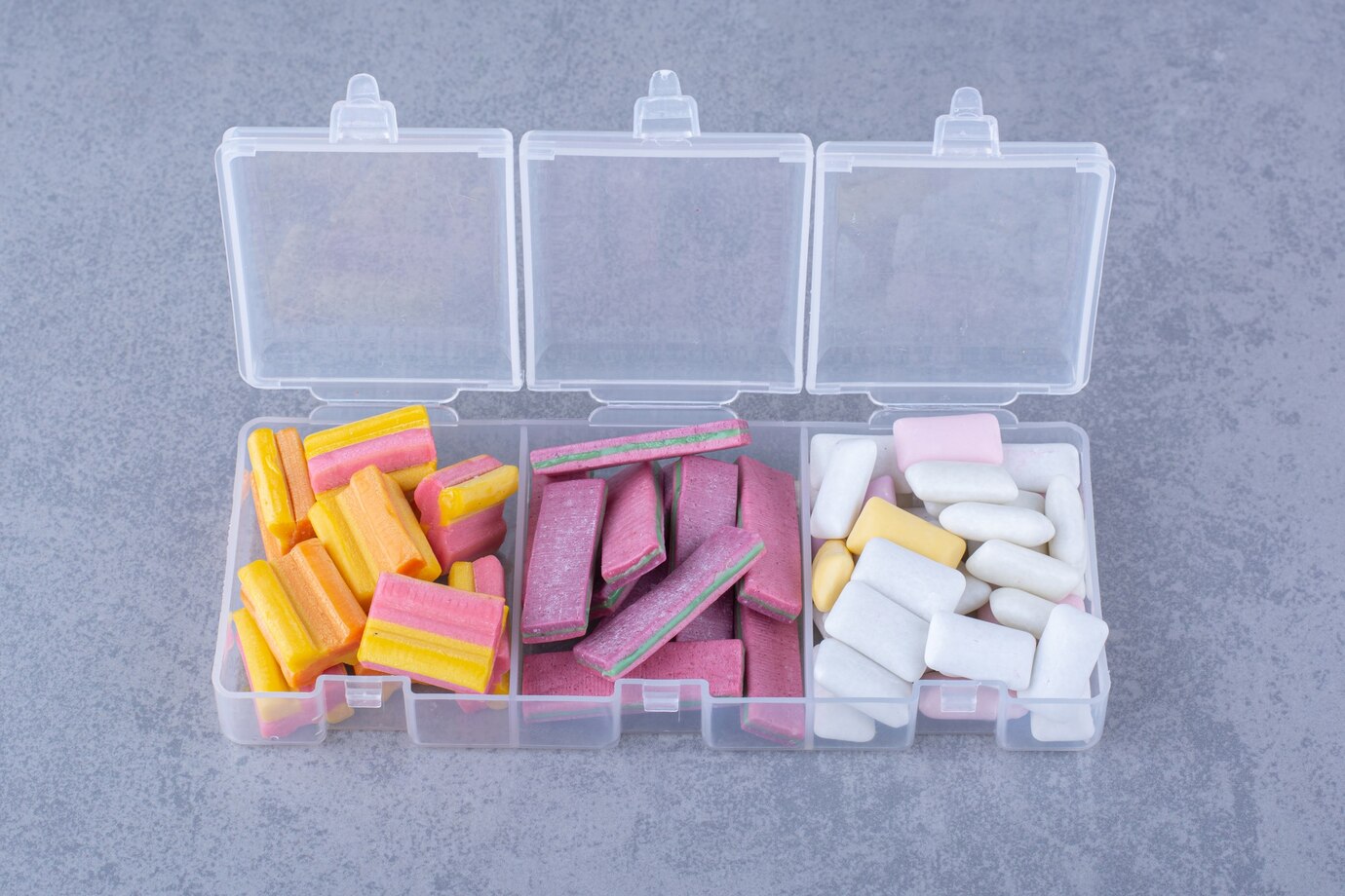 Assorted bundles of bubblegums neatly piled in small containers on marble surface