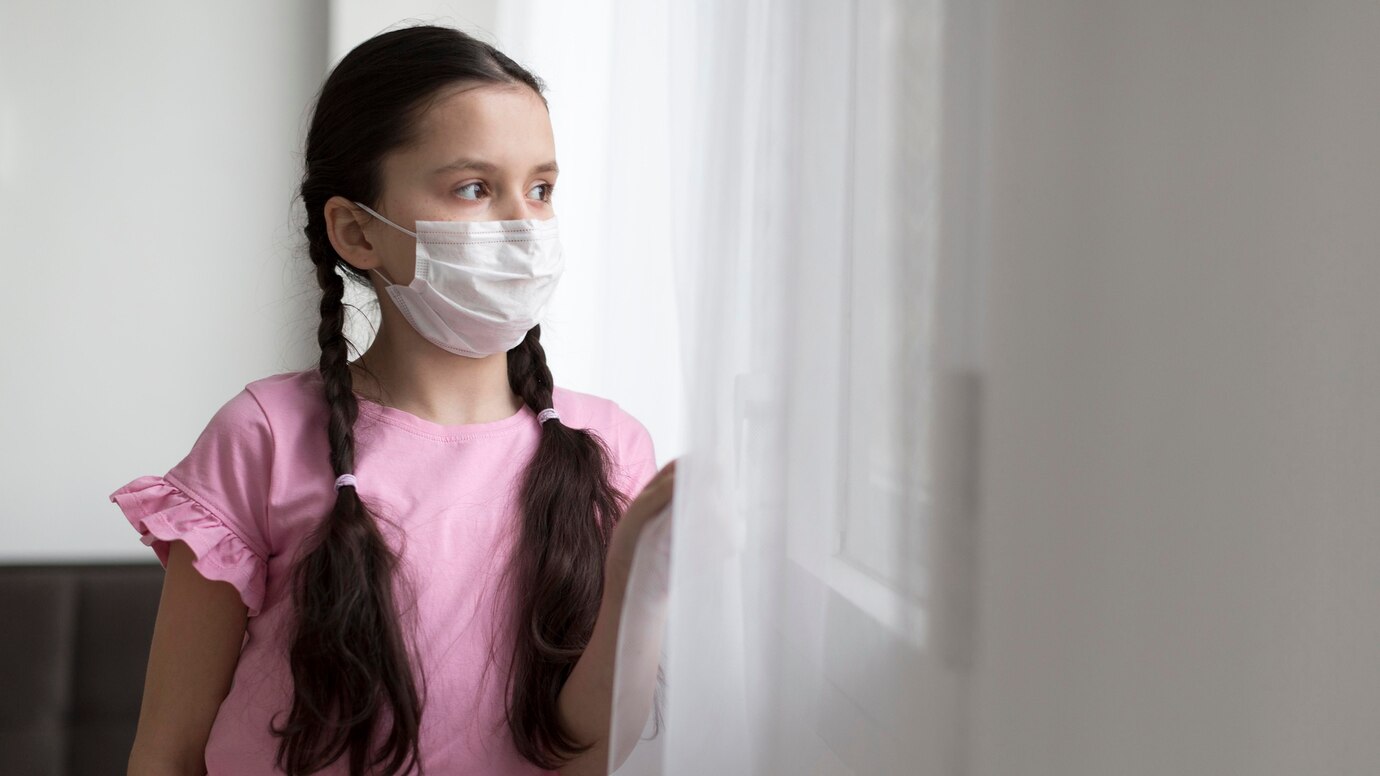 Child with mask on and pink T-shirt