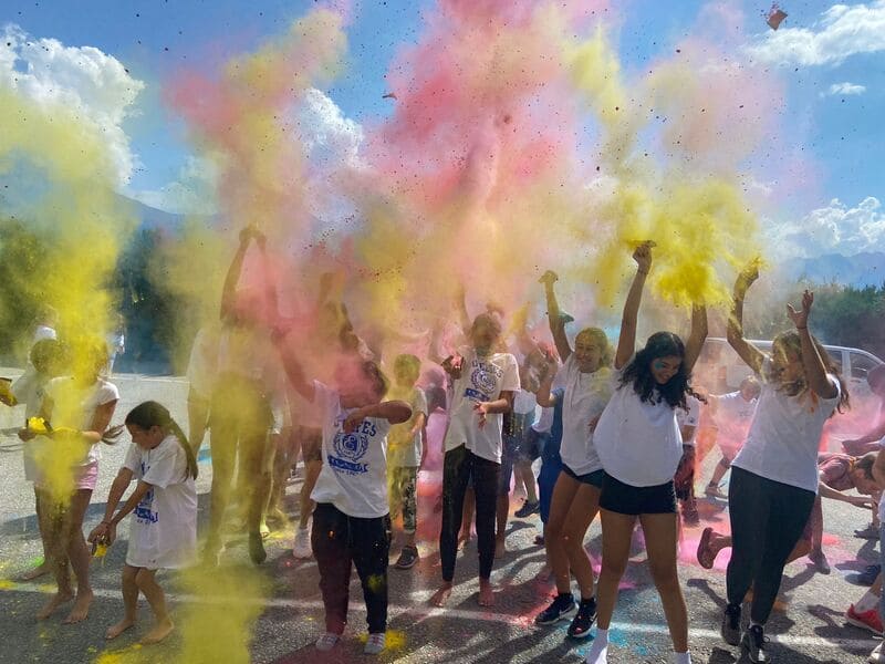 Group of many kids and teens throwing colors in the air during the Holi festival of International Day of the 2024 summer camp at les elfes international in Europe