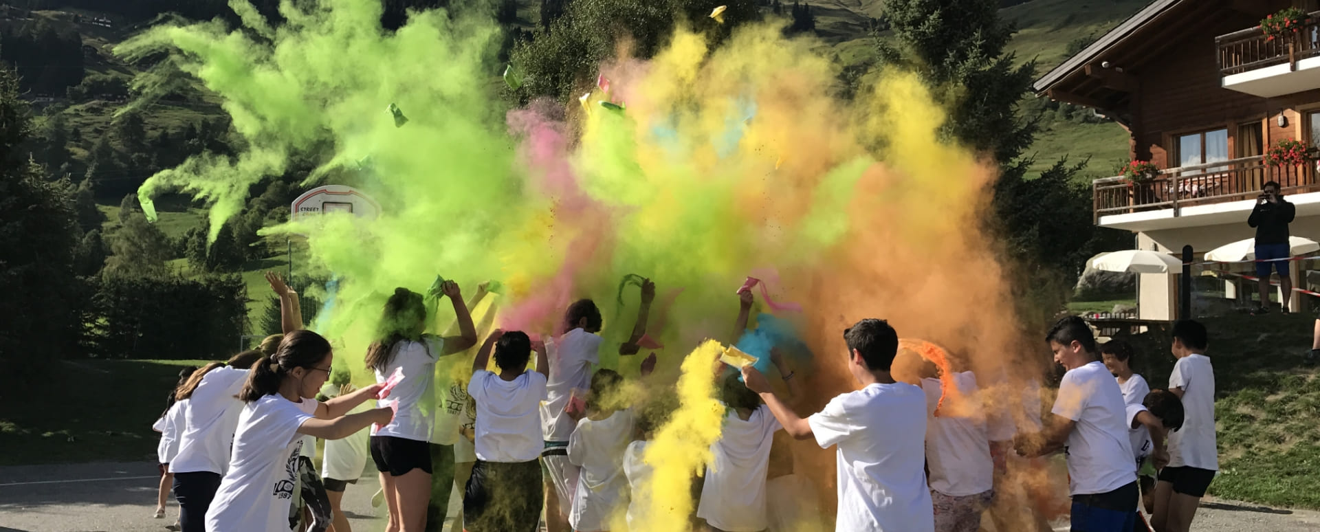 Group of kids throwing colors at each other like in the Indian Holi festival during their summer camp at Les Elfes international 2024 in Verbier, Switzerland, Europe