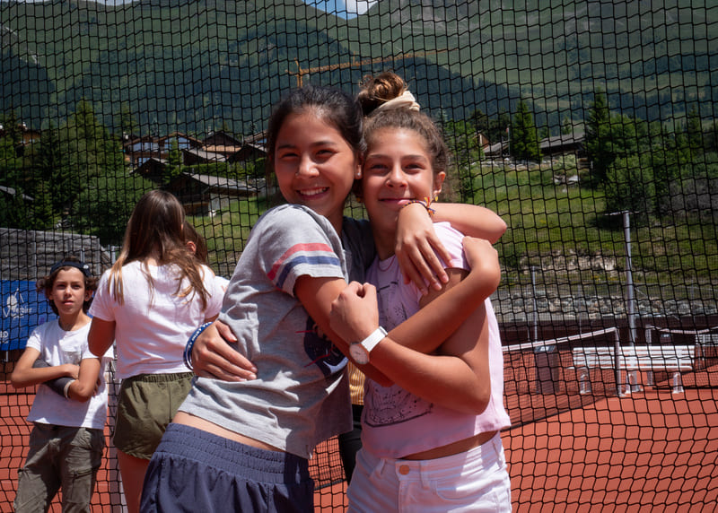 Two girls hugging each other after a tennis game during their 2024 summer camp in Les Elfes international Verbier, Switzerland, Europe