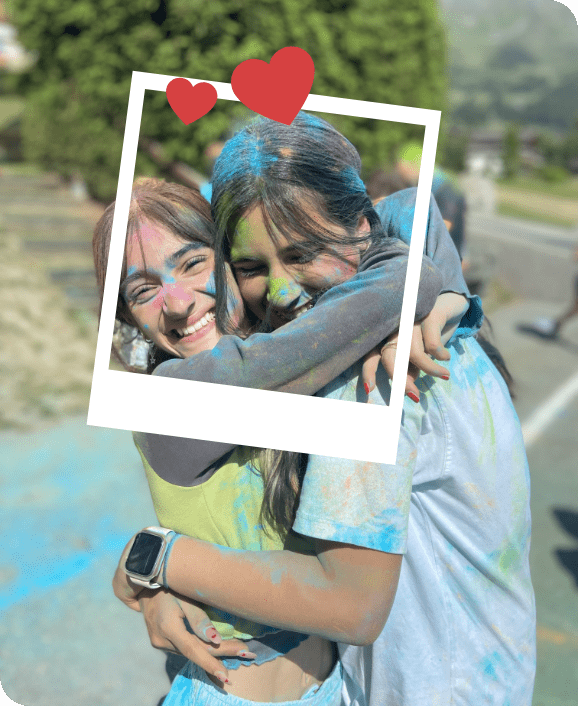 Two teens that became friends during the 2024 summer camp hug each other after throwing blue colors at each other for fun at Les Elfes International Camp in Verbier, Europe